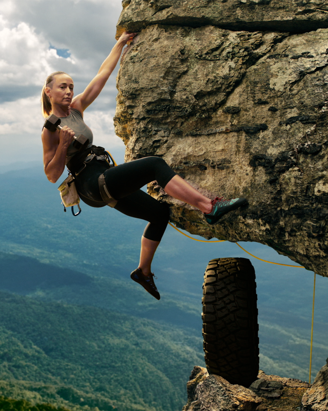 a woman rock climbing off a steep ledge while curling a weight, a toyo tire sits gently on the edge